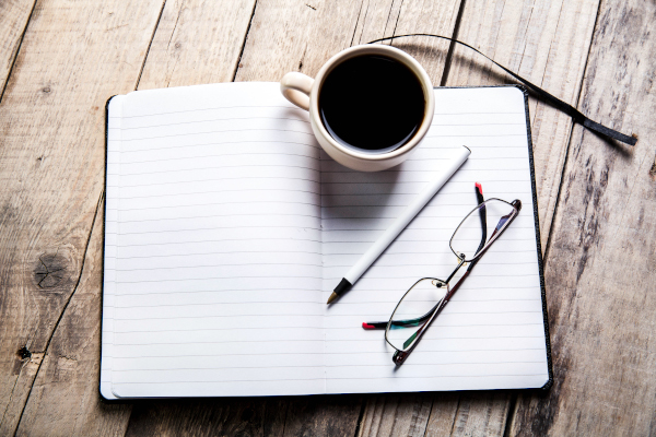 glasses-on-notebook-with-pen-and-cup